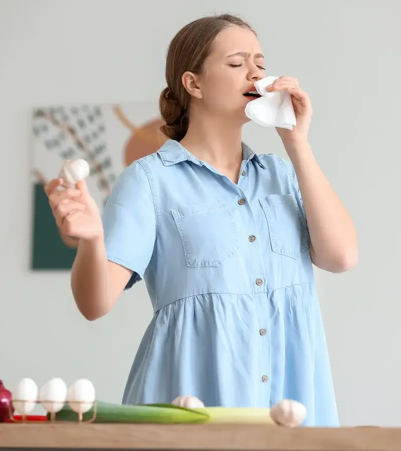 an image of a woman holding a garlic bulb and sneezing